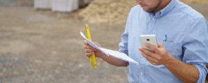 Man looking at phone, ruler and document